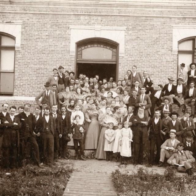 A group of students and faculty gathers for a photo in front of one of the buildings of AddRan Christian University in 1895