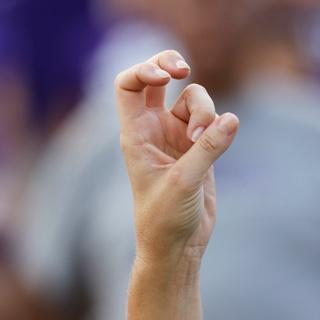 A close up of a young woman's hand making two-fingered "Go Frogs" hand sign.