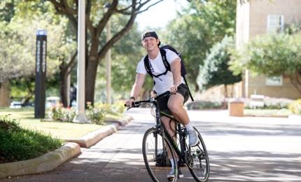 Male student riding a bike on campus