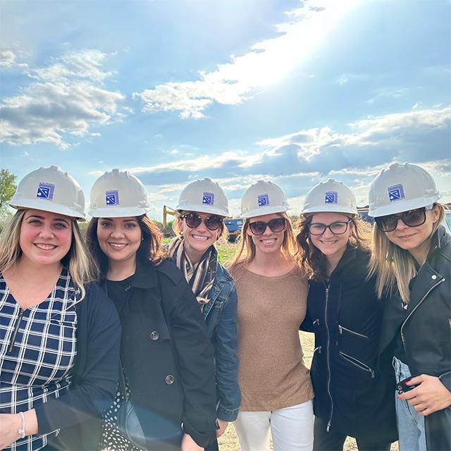 Faculty and students wear hard hats while visiting a field site